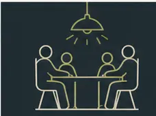 People playing cards together under a pendant light